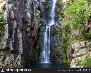 Beautiful waterfall of Veu da Noiva between the covered stones of moss and the vegetation located in an area of   completely preserved nature in the state of Minas Gerais, Brazil. Veu da Noiva waterfall  located in an area of   preserved nature