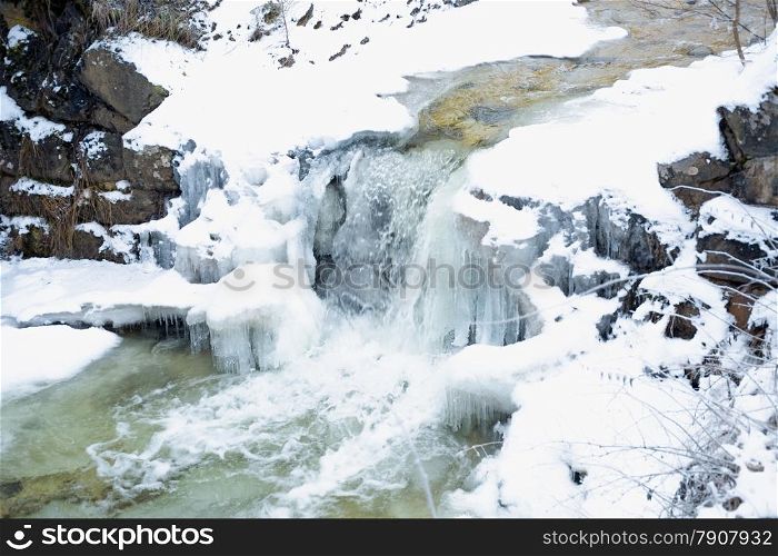 Beautiful waterfall on fast mountain river at winter