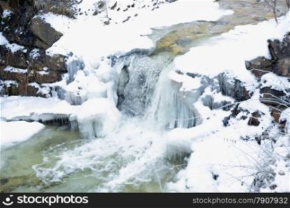 Beautiful waterfall on fast mountain river at winter