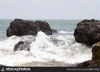 Beautiful waves of a beach of Goa, India. Wave crashing on the rocky reef.