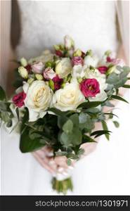 Beautiful wedding bouquet in hands of the bride. Shallow depth of field.