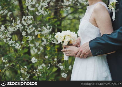 Beautiful wedding bouquet in hands of the newly-married couple on wedding.