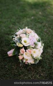 beautiful wedding bouquet of white flowers lies on the grass close up. beautiful wedding bouquet of white flowers lies on the grass