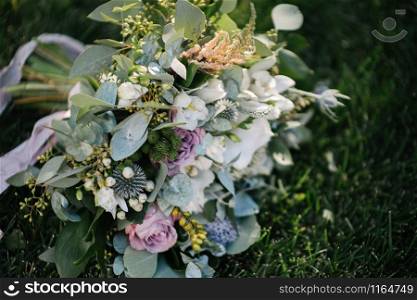 beautiful wedding bouquet of white flowers lies on the grass close up. beautiful wedding bouquet of white flowers lies on the grass