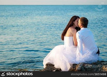 Beautiful wedding couple- bride and groom kissing at the beach. Just married