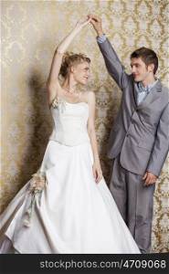 Beautiful wedding couple posing together. Blonde woman in long white dress. Handsome man in suit. Studio shot.