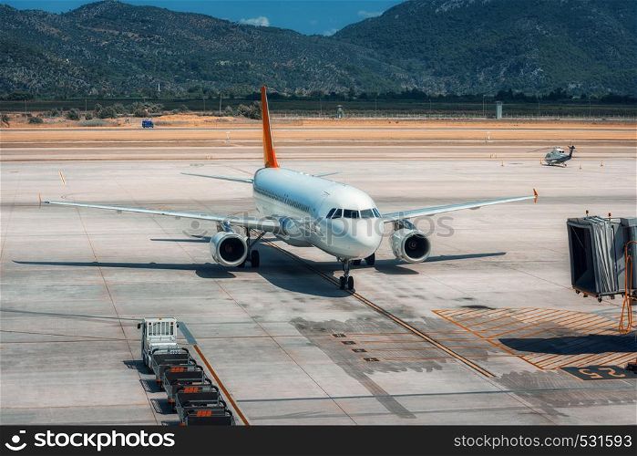 Beautiful white airplane on the runway in Dalaman airport. Landscape with big passenger airplane is taking off and mountains at bright sunny day in summer. Business trip. Commercial aircraft. Travel. Beautiful white airplane on the runway in Dalaman airport