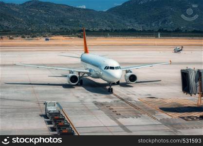 Beautiful white airplane on the runway in Dalaman airport. Landscape with big passenger airplane is taking off and mountains at bright sunny day in summer. Business trip. Commercial aircraft. Travel. Beautiful white airplane on the runway in Dalaman airport