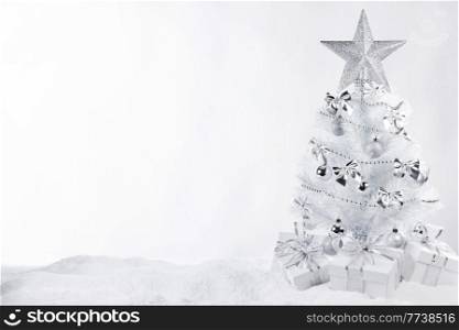 Beautiful white Christmas tree on snow decorated with balls and star isolated on white background. White ornate Christmas tree
