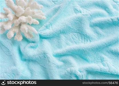 Beautiful white sea coral on the background of cotton terry blue towel, crumpled by waves