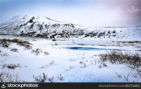 Beautiful winter landscape, amazing panoramic view on the little frozen lake and majestic mountains behind it, extreme travel to Iceland
