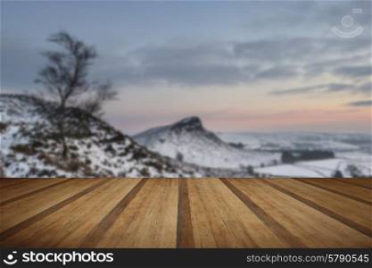 Beautiful Winter landscape at sunset over snow covered countryside with wooden planks floor