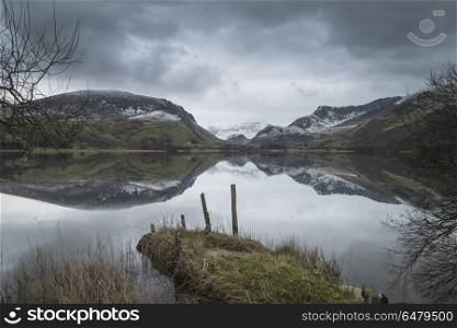 Beautiful Winter landscape image of Llyn Nantlle in Snowdonia Na. Beautiful sunrise landscape image in Winter of Llyn Nantlle in Snowdonia National Park with snow capped mountains in background