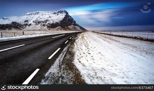 Beautiful winter landscape of a road, empty highway, peaceful view on the great mountain covered with snow, wintertime in Iceland
