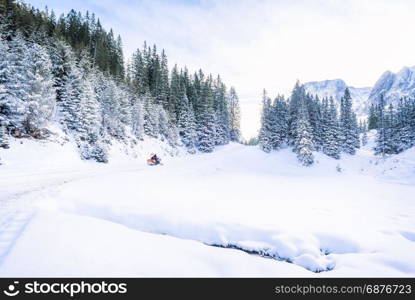 Beautiful winter landscape with fir forests, the peaks of Austrian Alps mountains and a road, everything covered in snow, on a sunny day of December.