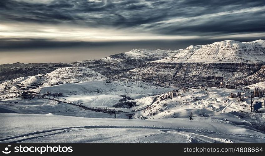 Beautiful winter mountains landscape, mountain village covered with snow, ski resort on a cold dark day