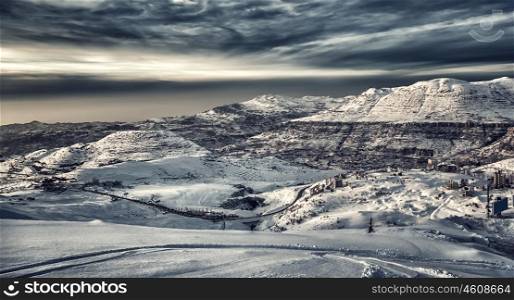 Beautiful winter mountains landscape, mountain village covered with snow, ski resort on a cold dark day