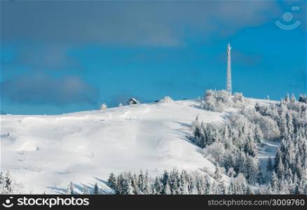 Beautiful winter rime frosting trees, communication tower and snowdrifts on mountain top on blue cloudy sky background (Carpathian mountain, Ukraine). People are unrecognizable.