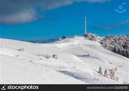 Beautiful winter rime frosting trees, communication tower and snowdrifts on mountain top on blue cloudy sky background (Carpathian mountains, Ukraine)