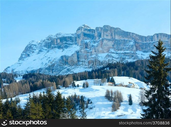 Beautiful winter rocky mountain landscape and houses on slope. Italy Dolomites, at the foot of Passo Gardena, South Tyrol.