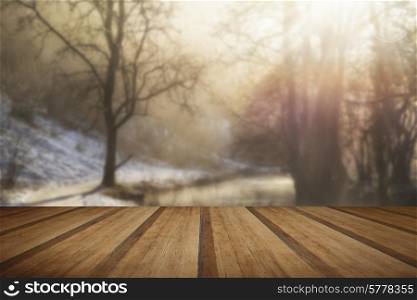 Beautiful Winter snow covered countryside landscape of river flowing with reflections with wooden planks floor