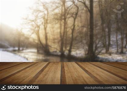 Beautiful Winter snow covered countryside landscape of river flowing with reflections with wooden planks floor