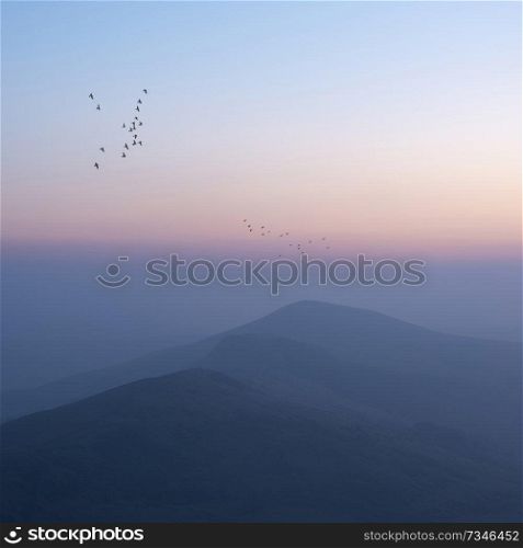 Beautiful Winter sunrise landscape image of The Great Ridge in the Peak District in England with  birds flying around the peaks