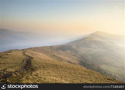 Beautiful Winter sunrise landscape image of The Great Ridge in the Peak District in England with mist hanging around the peaks