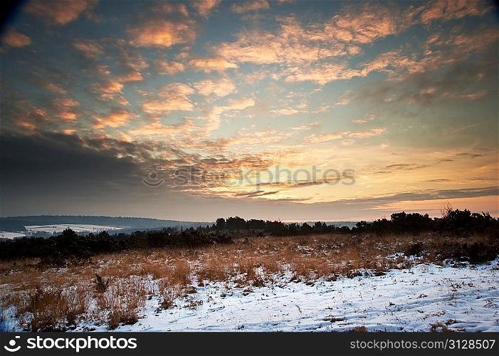 Beautiful Winter sunrise landscape over vibrant snow covered countryside landscape