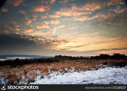Beautiful Winter sunrise landscape over vibrant snow covered countryside landscape