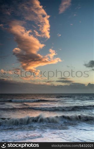 Beautiful Winter sunset sky over long exposure waves in ocean