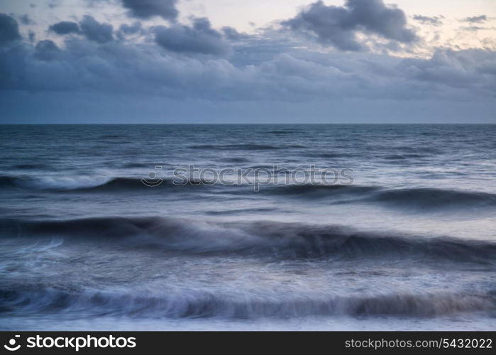 Beautiful Winter sunset sky over long exposure waves in ocean