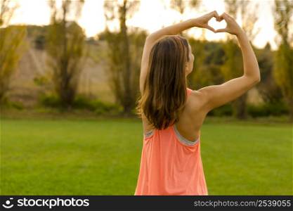 Beautiful woman after the exercise making a hearth shape