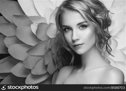 Beautiful woman against a large chrysanthemum flower. Young woman with elegant hair and makeup. Fashionable black and white photography