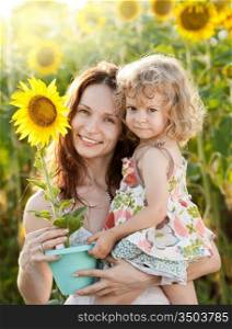 Beautiful woman and child with sunflower in spring field
