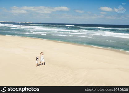 Beautiful woman and her little daughter walking on the beach