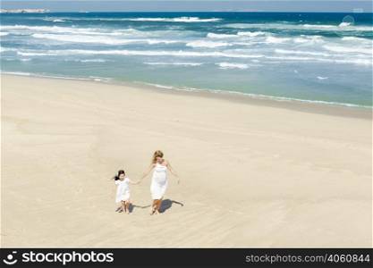 Beautiful woman and her little daughter walking on the beach
