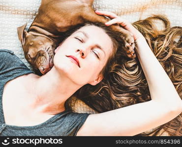 Beautiful woman and young, charming puppy, resting on a plaid. Close-up, white isolated background. Studio photo. Concept of care, education, training and raising of animals. Woman and puppy resting on a plaid