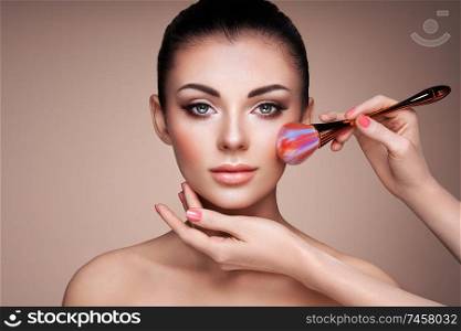 Beautiful Woman applies Skin Tone with Brush. Beautiful Woman face. Perfect Makeup. Skincare Foundation. Brushes Makeup Artist
