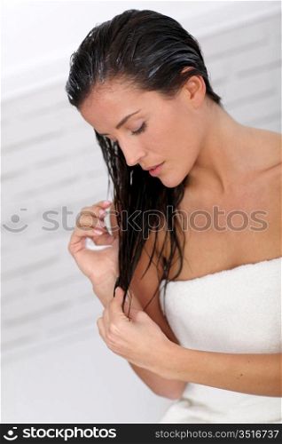 Beautiful woman applying hair conditioner