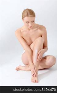 Beautiful woman applying moisturizer on her legs