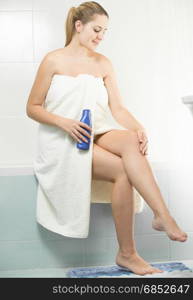 Beautiful woman applying moisturizing creme after shaving legs