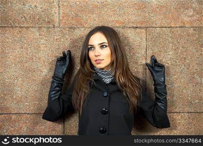 Beautiful woman at a wall with heaved up hands