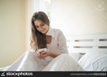 Beautiful woman at her bedroom drinking coffee in the morning