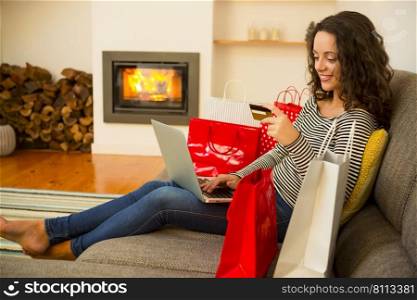 Beautiful woman at home at the warmth of the fireplace, shopping online