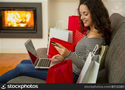 Beautiful woman at home at the warmth of the fireplace, shopping online