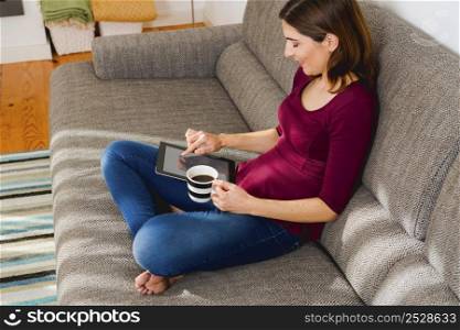 Beautiful woman at home in the sofa and working with a tablet