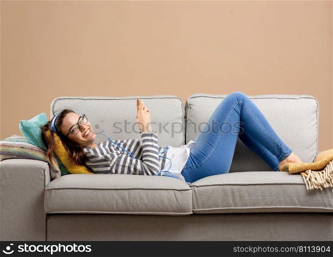 Beautiful woman at home lying on the sofa and listen music