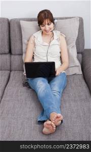 Beautiful woman at home seated on sofa, and speaking online over the internet