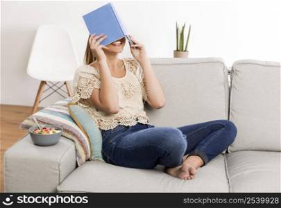 Beautiful woman at home sitting on the couch and reading a book